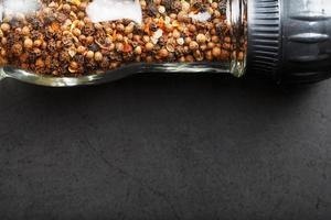 A mixture of seasonings, spices and herbs in a glass mill on a black background. photo