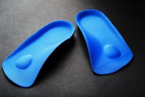 plantillas ortopédicas para la corrección del color azul del pie sobre un fondo negro. foto