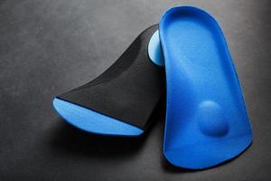 Orthopedic insoles for correction of the blue color of the foot on a black background. photo