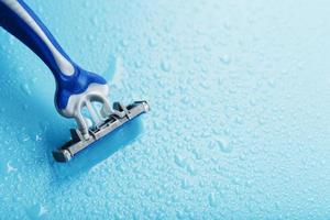 cuchillas de afeitar sobre un fondo azul con gotas de agua helada foto