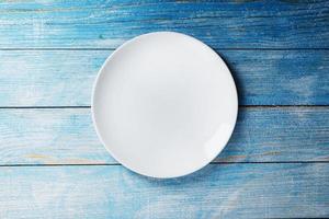 White plate on a blue background top view. photo