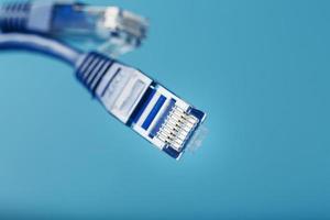 Two Ethernet Cable Connectors Patch cord cord close-up isolated on a blue background with free space photo