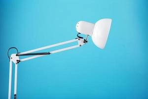 White table office lamp on blue background with space for text and idea concept photo