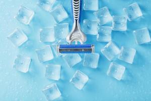 Blue shaving machine with sharp blades on the background of ice cubes close-up photo