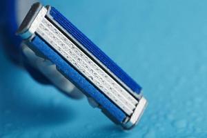 Razor blades on a blue background with drops of icy water photo