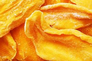 Pieces of sweet dried mango close-up as a background in full screen photo