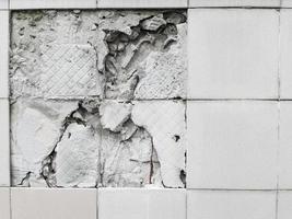 A wall with a broken off gray tile from the wall photo