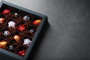 un conjunto de coloridos chocolates hechos a mano exclusivos en una caja sobre un fondo negro. foto