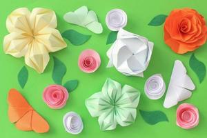 Origami paper background with butterflies, flowers and leaves on green background. Origami composition. Paper craft photo