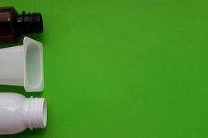 Plastic bottles on the left side of green background with place for your design. Top view photo