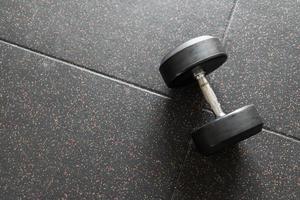 Black dumbbell. Weight Training Equipment. black dumbbells on the floor in dark concept fitness room with training equipments photo