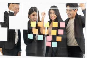 businesspeople office worker reading sticky notes on planning glass board. Business team pointing on keywords in sticky notes and business report to brainstorming about planning strategy of business. photo