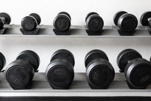 Stand with dumbbells. Sports and fitness room. Weight Training Equipment. Black dumbbell set, many dumbbells on rack in sport fitness center photo