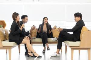 Business couple sitting together with coffee cup near the window background. Young business people with coffee cup laughing while sitting with friends. photo