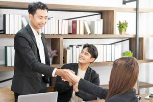 Welcome to our team. young modern men and woman in smart casual wear shaking hands. Three smiling businesspeople shaking hands together. photo