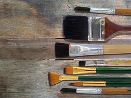 Brush art supplies on old wooden table, Top view photo