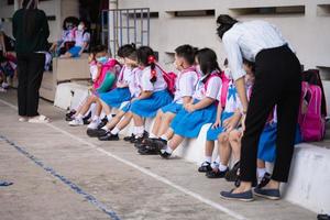 bangkok tailandia-20 de mayo de 2022. los niños de kindergarten están esperando que sus padres regresen a casa después de la escuela. el maestro está parado cerca. foto