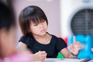 Asian cute girl doing art on table. Kid thinking and imagination with craft workshop. Homeschool with sibling family. Child aged 5 - 6 years old wearing black t-shirt. photo