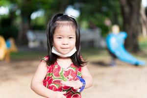 Cute girl played in playground until she was tired. Asian child sweats on the temples. Children smiles sweet. In summer or spring. Happy kids wearing a red shirt is 3-4 years old. photo