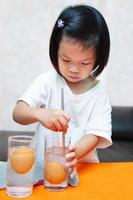 Student learning and doing principles science experiments. Sinking Egg Experiment - Floating eggs with water and salted water. Girl is using metal rod stir to dissolve salt in water. Doing it yourself photo