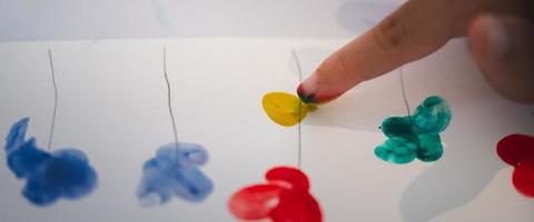 Art from fingers concept. Little children use her fingers to paint different colors on paper. Learn through play. photo