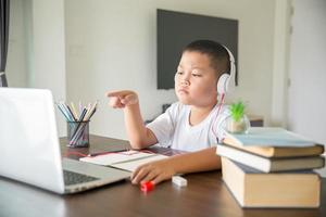 joven estudiante aprendiendo a distancia clase virtual a distancia en línea en videollamada lección virtual, tecnología estudiando en casa usando una computadora portátil. padre o tutor enseñando a un niño con educación remota. foto