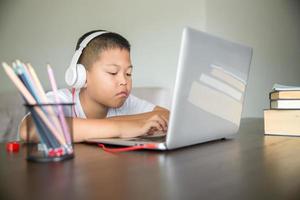 joven estudiante aprendiendo a distancia clase virtual a distancia en línea en videollamada lección virtual, tecnología estudiando en casa usando una computadora portátil. padre o tutor enseñando a un niño con educación remota. foto