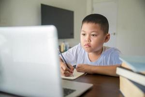 Young student distance learning virtual distance online class on video call virtual lesson, technology studying at home using laptop computer. Parent or tutor teaching child boy with remote education. photo