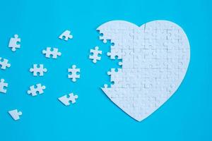 White heart shape of jigsaw puzzle pieces on blue background. concepts of problem solving, business success, teamwork, Team playing jigsaw game incomplete, Texture banner with copy space for text photo