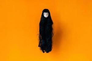 Long hair female ghost doll flying on orange background. Minimal Halloween scary concept. photo