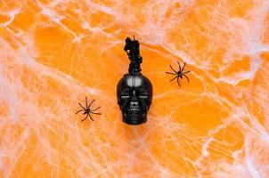 Scary halloween background with skull that have candle on top puts on orange background with spider and cobweb. photo
