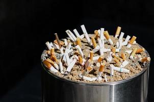 The big ashtray with many focus and blurred cigarettes that smokers only can smoke in the limit smoking area. photo
