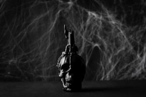 Black candle on skull with cobweb on black background. Halloween concept. photo