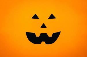 fondo de cara de calabaza de halloween de cortar papel naranja y negro. concepto mínimo de halloween. foto
