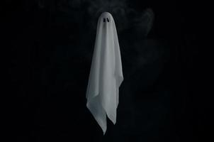 Blurred focus of white ghost sheet in dark background with smoke. Halloween scary concept. photo