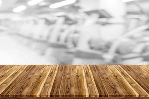 Empty wooden board space platform with blur fitness gym equipment background photo