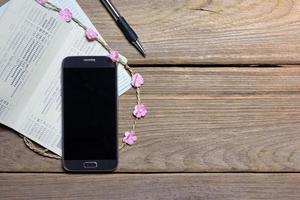 teléfono inteligente y libro de cuentas sobre fondo de madera, concepto de negocio foto