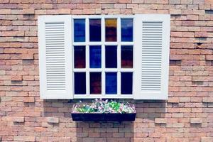 ventana de madera blanca y maceta de flores sobre fondo de pared de ladrillo, efecto de filtro foto