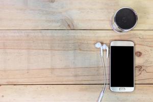 teléfono móvil inteligente con auricular sobre fondo de madera foto