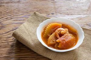 Sour curry shrimp and papaya on wood background photo