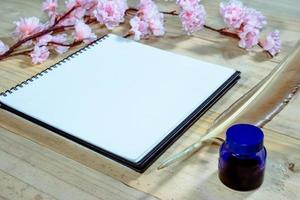 open note book with pink sakura flowers on wooden background,filter effect. photo