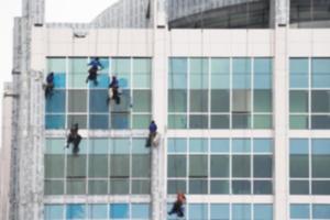 trabajadores que limpian el servicio de ventanas en un edificio de gran altura, fondo borroso foto