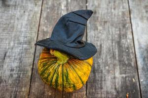 Jack O Lantern Halloween pumpkin with black witch hat on wooden background. Halloween party concept. Holiday season greeting, trick of treat spooky. photo