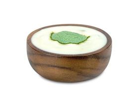 yogur con nata de coco dutche y polvo de sabor a té verde en un tazón de madera aislado en fondo blanco, incluye camino de recorte foto