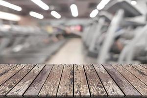 Empty wooden board space platform with blur fitness gym equipment background photo