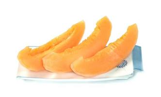 Fruta de melón cantalupo naranja cortada en un plato aislado de fondo blanco foto