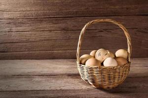 huevos en una cesta de mimbre sobre una mesa de madera foto