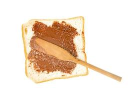 Toasted slice bread with chocolate spread and wooden spatula isolated on white background photo