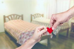 hand holding heart-shaped with blur bedroom photo