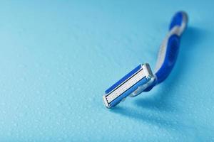 Razor blades on a blue background with drops of icy water photo